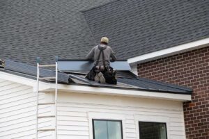 Close view of bruised asphalt shingles with missing granules beside dented metal roof flashing.